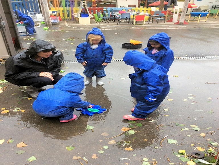 Nursery children playing outside in the wet weather