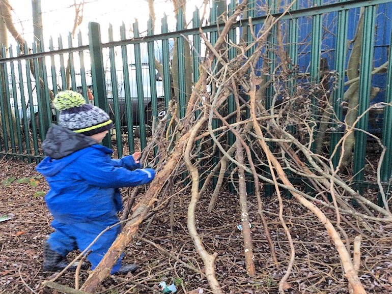 A child building a shelter with tree branches